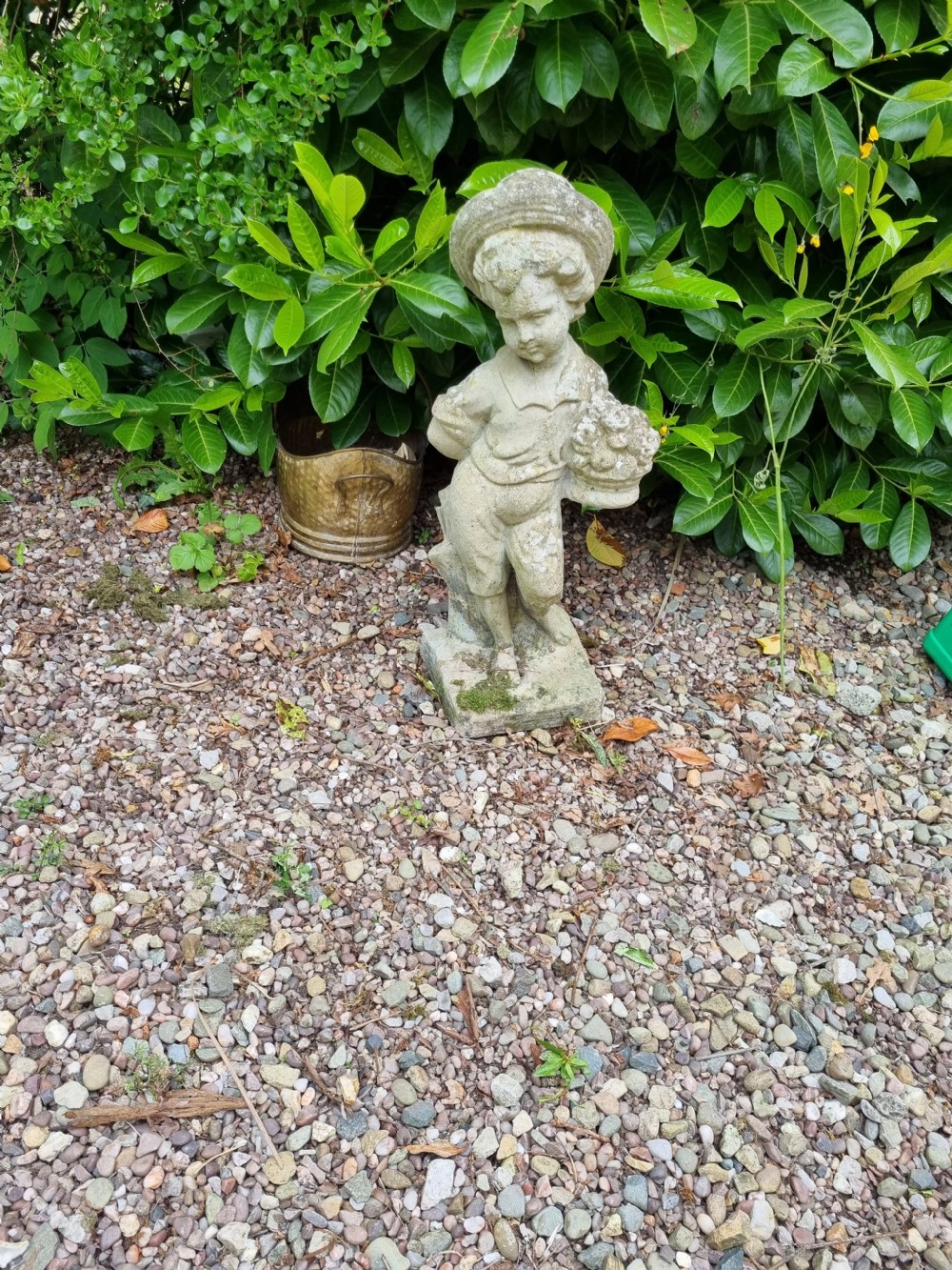 a weathered stone statueof a boy with basket